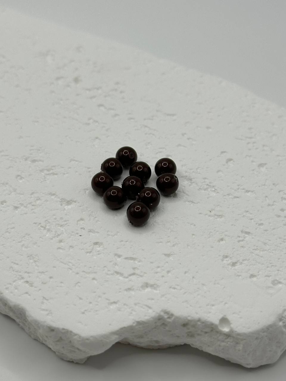 Maroon crystal pearls on a textured white surface