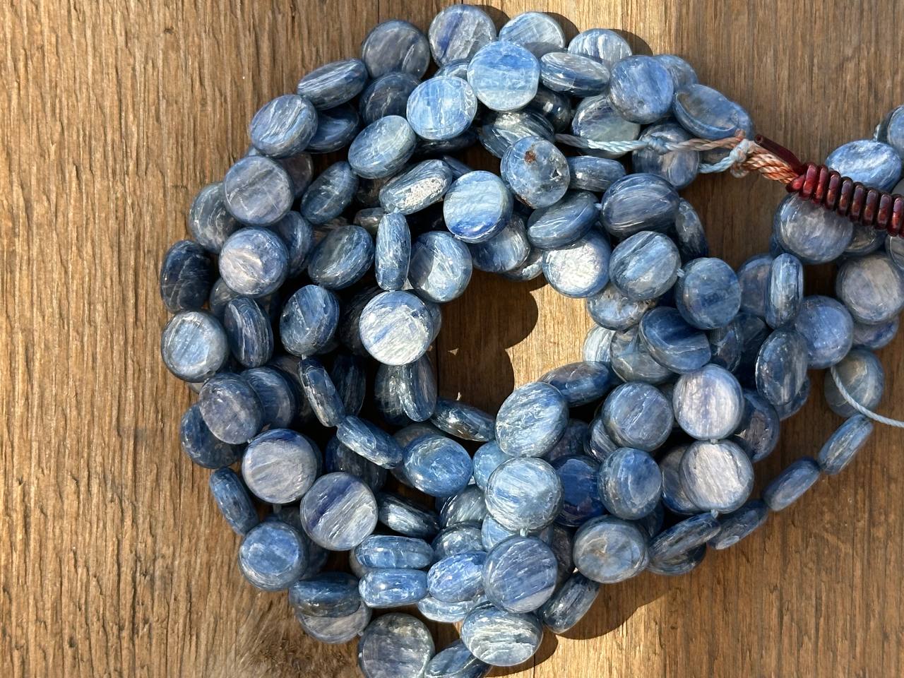 Blue flat oval 10mm kyanite beads on a wooden surface