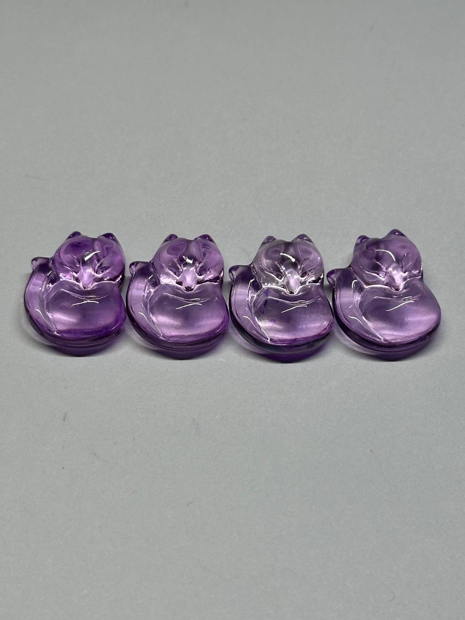 Four purple crystal animal figurines on a gray background