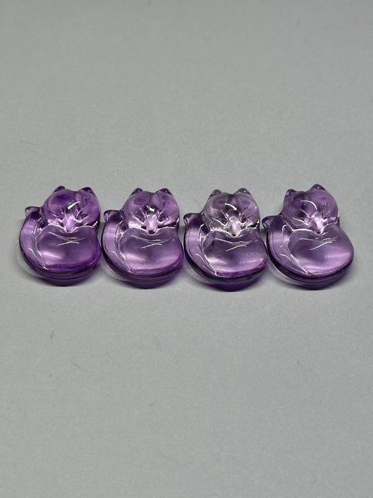 Four purple crystal animal figurines on a gray background