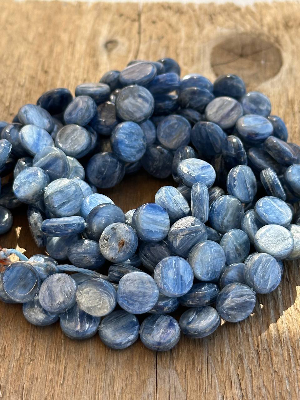 Blue kyanite flat oval beads on a wooden surface