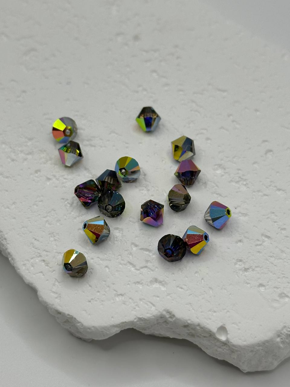 Multicolored crystal bicone beads on a textured white surface