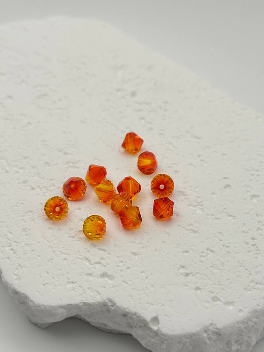 Orange and red bicone beads on a textured white surface