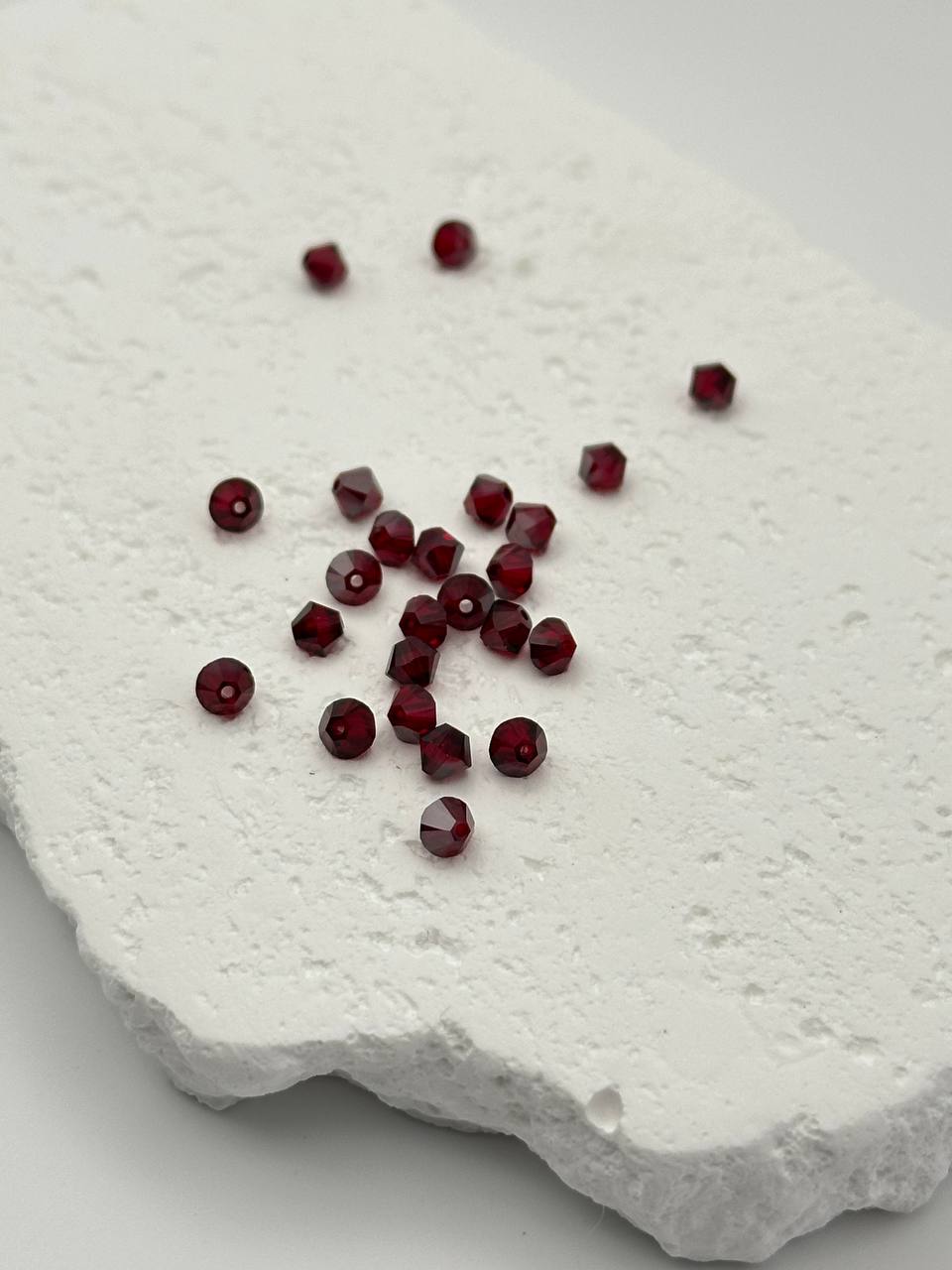 Dark red bicone beads on white surface