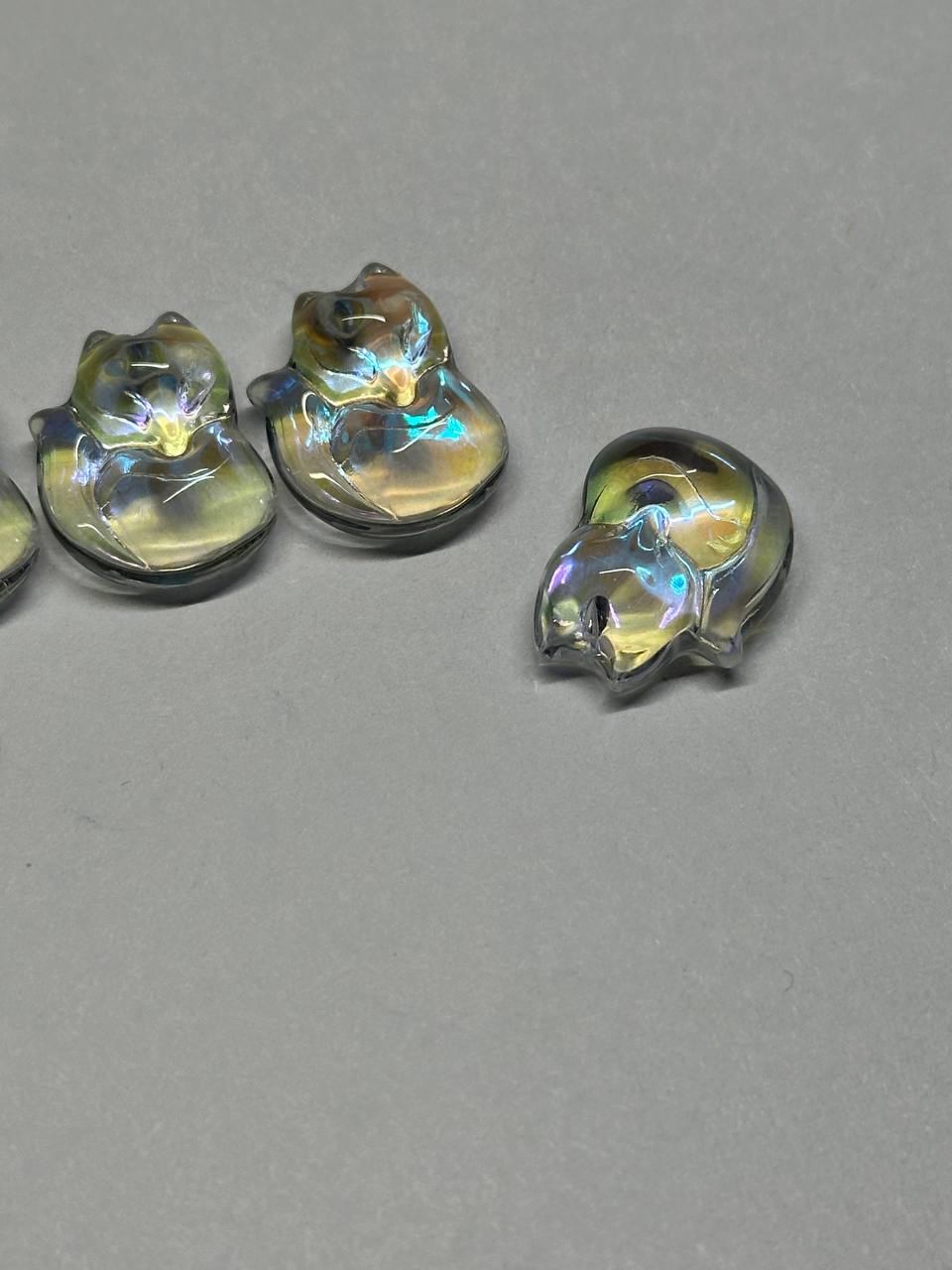 Iridescent glass fox-shaped objects on a gray background