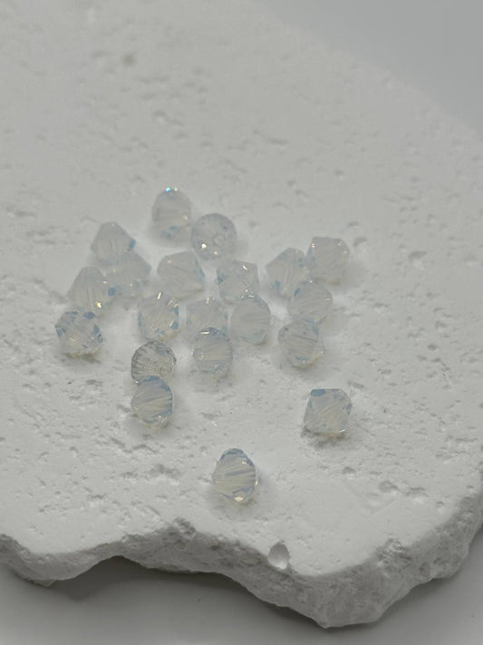 White opal crystal bicone beads with a metallic sheen on a textured white surface