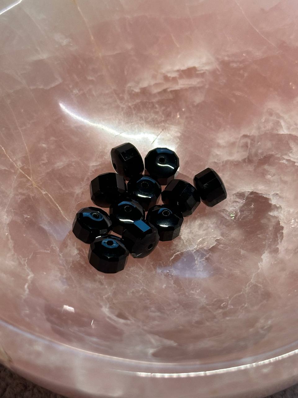 Black beads on a reflective pink surface