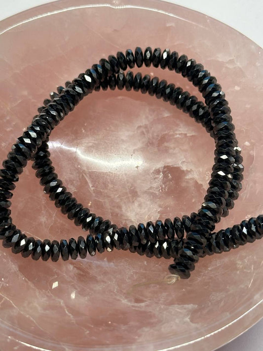 Black hemalyke faceted beads on a pink stone surface