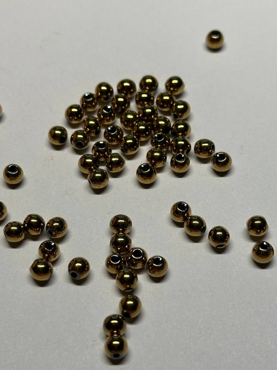 Small gold beads scattered on a white surface