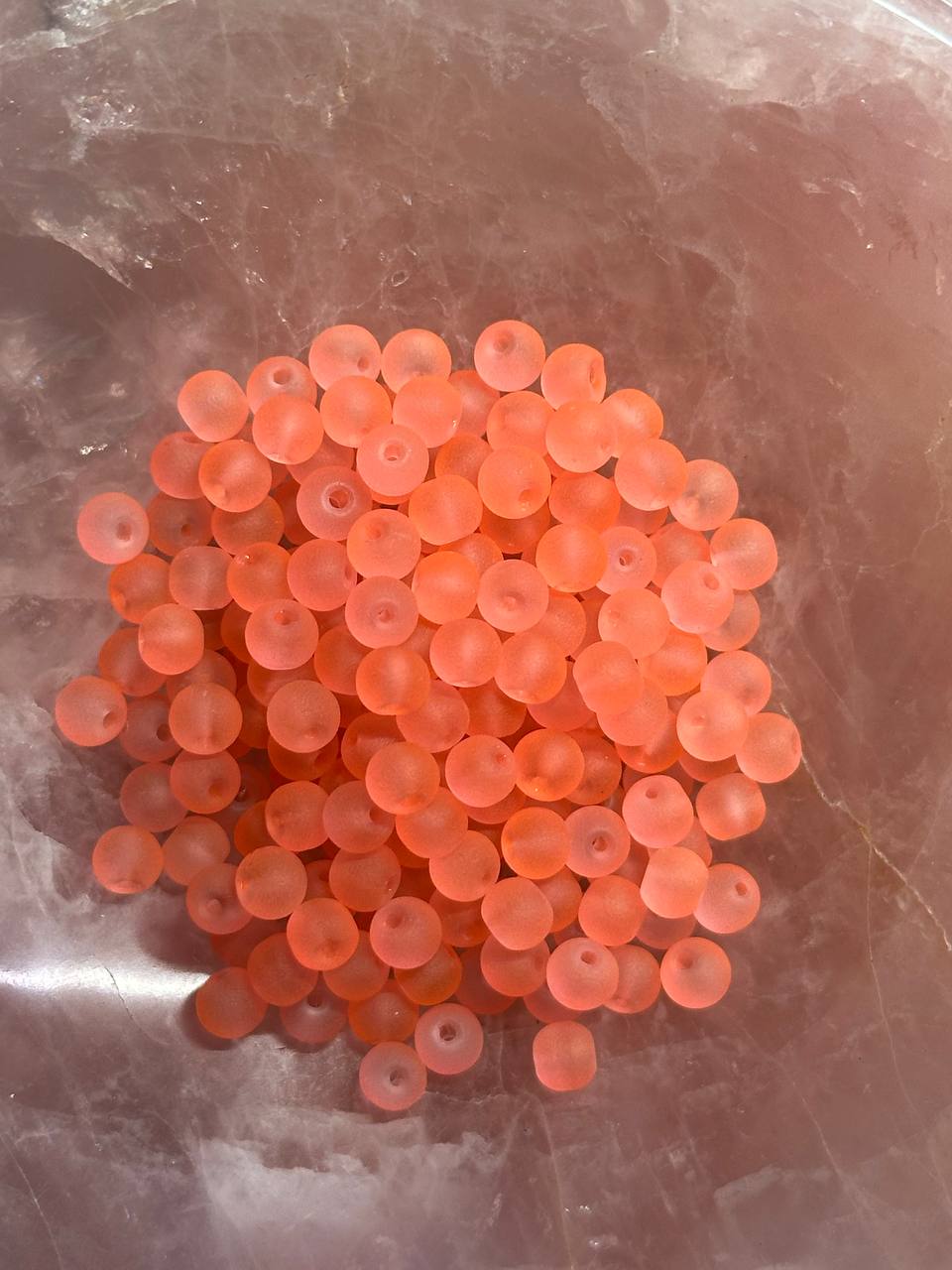 Cluster of small salmon beads on a reflective surface