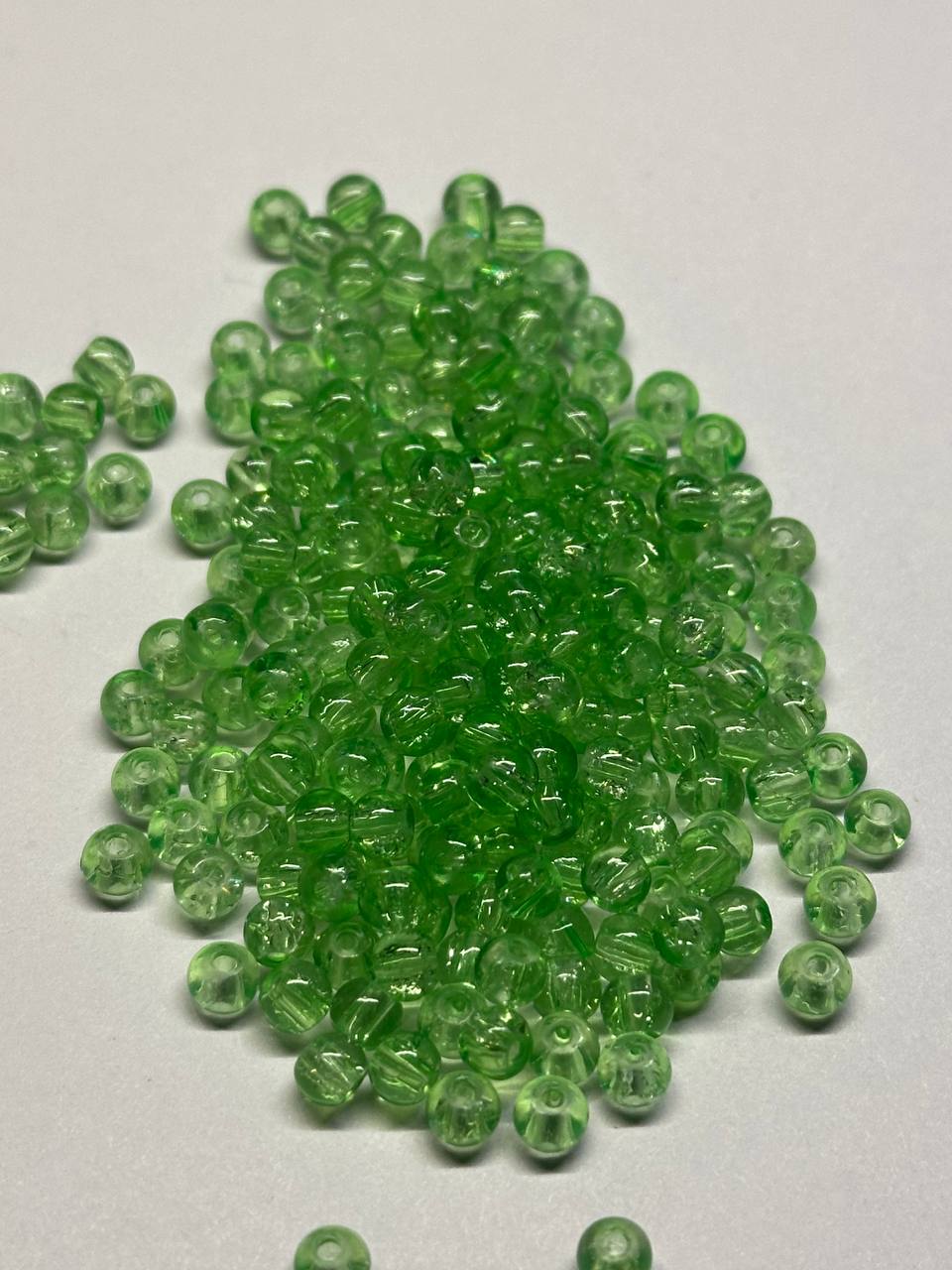 Green beads scattered on a white surface