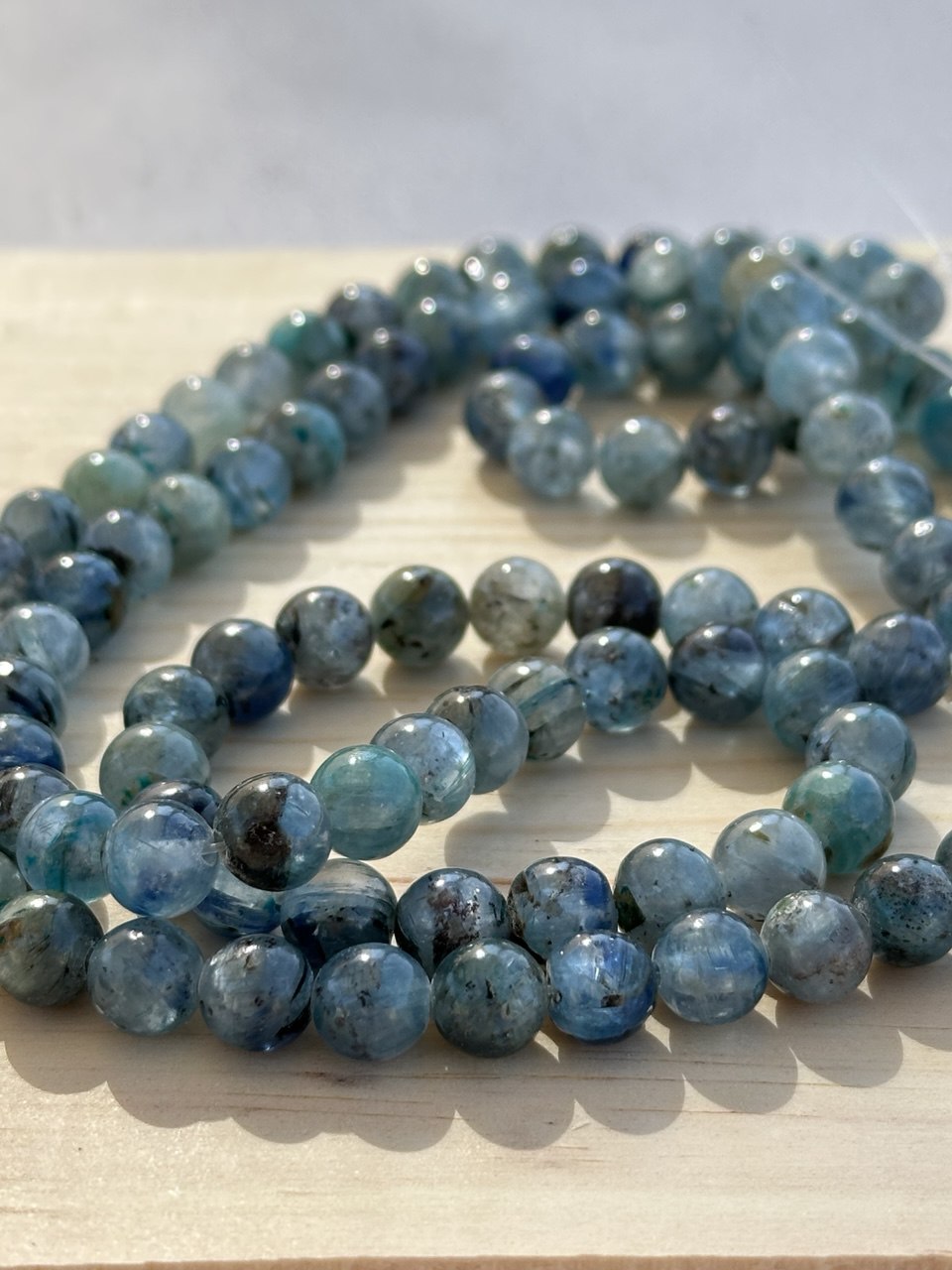 String of blue kyanite beads on a light wooden surface