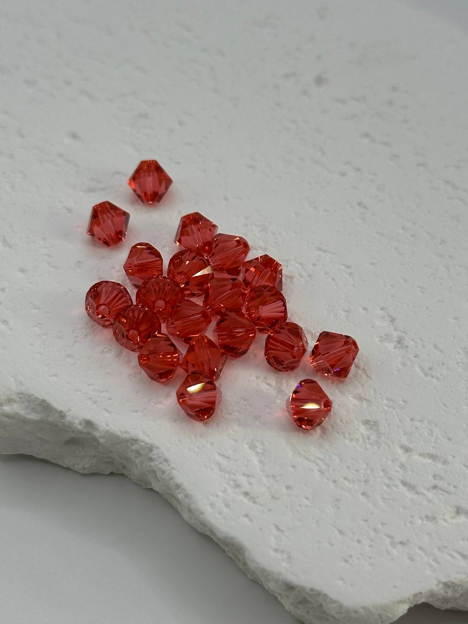 Padparadscha beads on a textured white surface