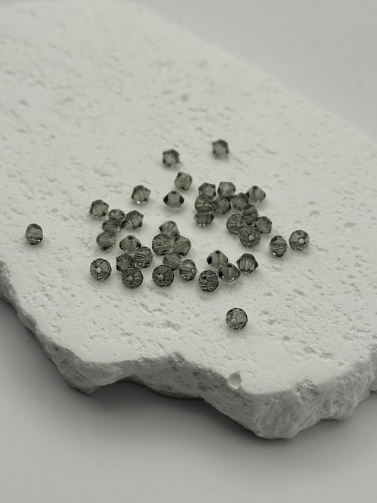 Small black diamond bicone beads on a textured white stone surface