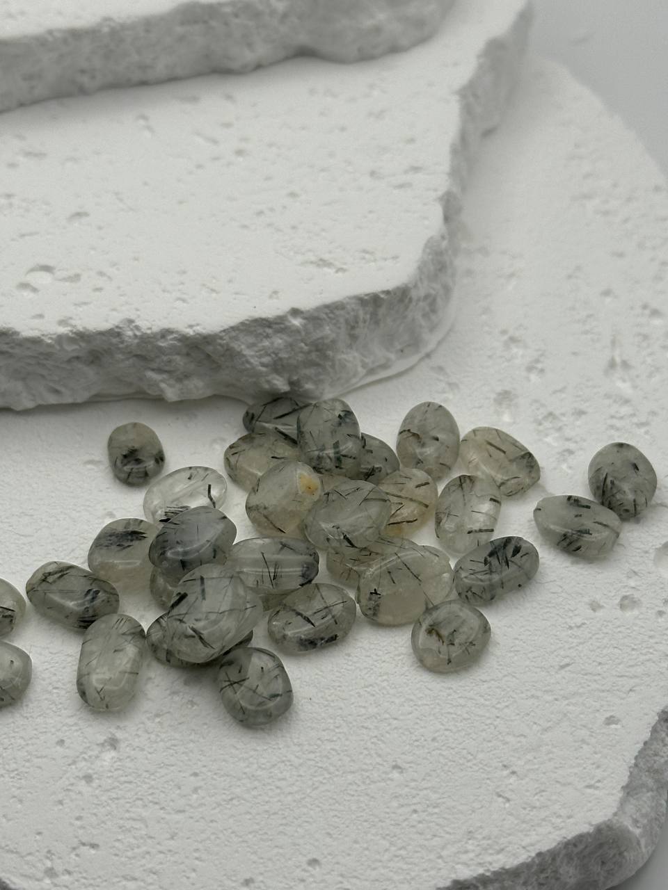 Small tourmalinated quartz beads on a textured white surface
