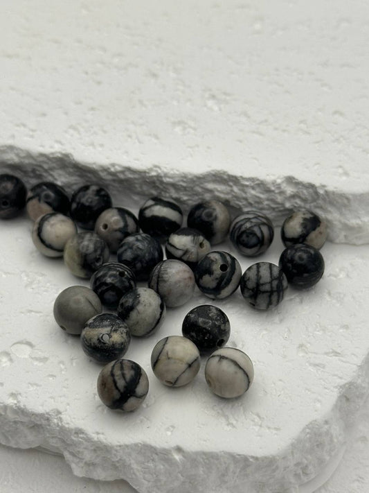 Black and white marbled beads on a textured stone surface