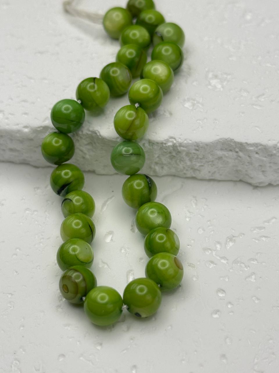 Green beaded necklace on a white surface