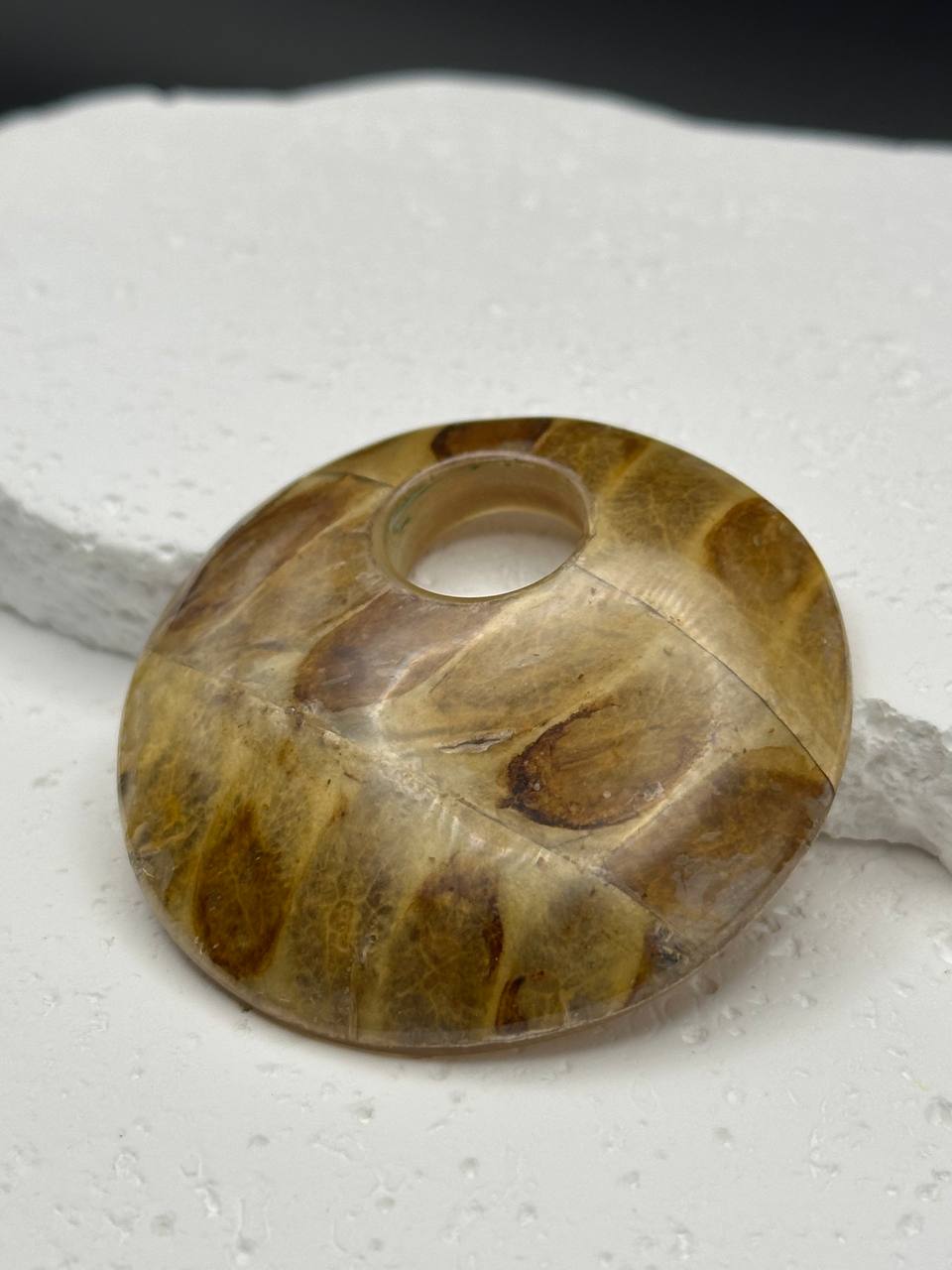 Brown stone pendant on a textured white surface