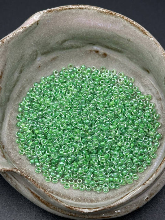 Green beads in a ceramic container on a dark background