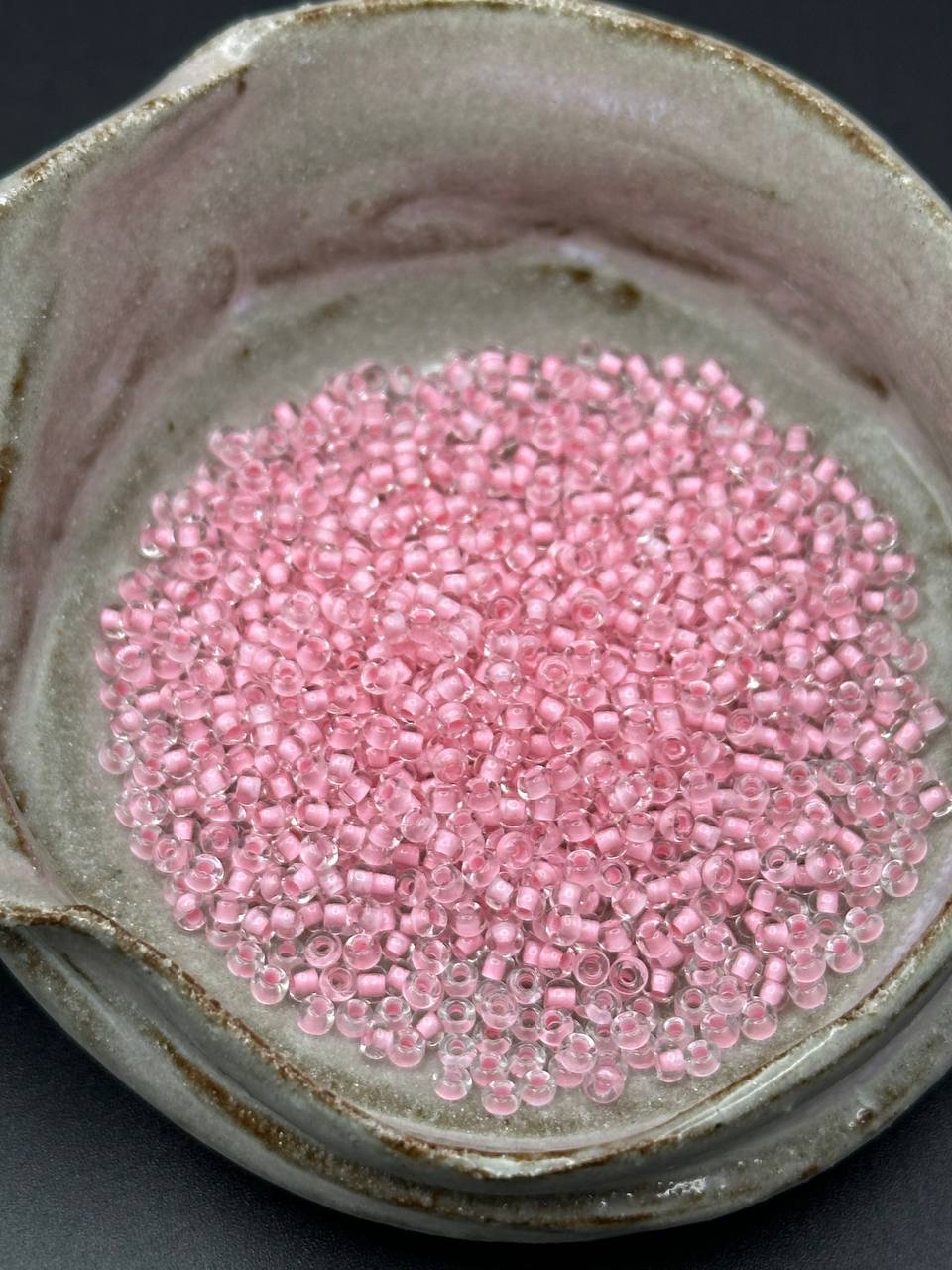 small container filled with pink silver lined beads