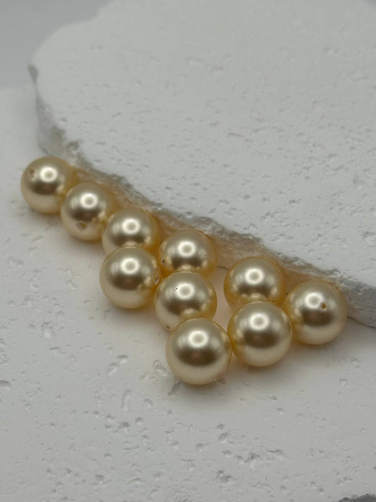 Gold colored pearl beads on a textured white surface
