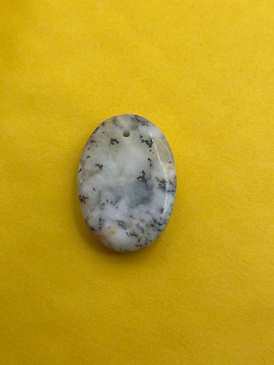 Oval-shaped stone with a hole on a yellow background