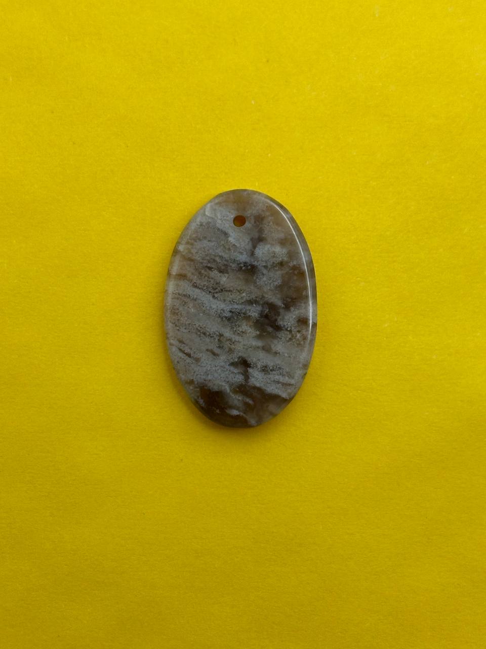 Oval-shaped stone with a hole on a yellow background