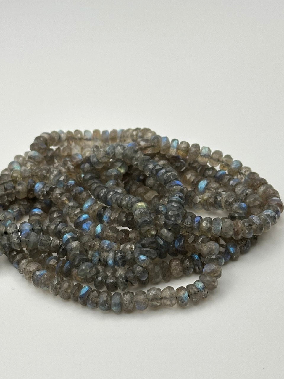 faceted rondelle labradorite beads on white surface
