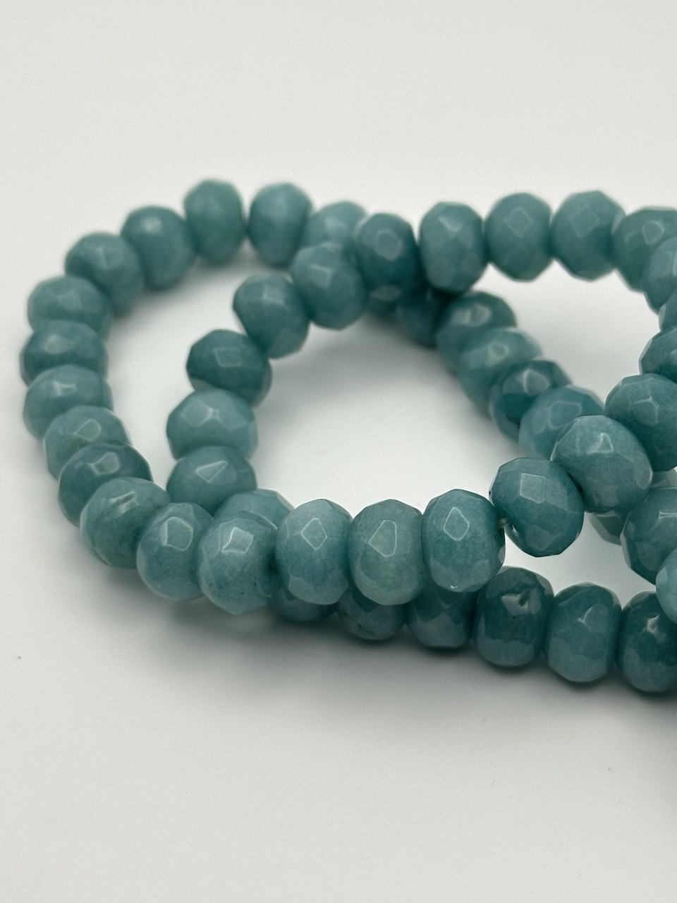 a string of teal aventurine beads on a white surface