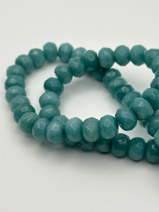 a string of teal aventurine beads on a white surface