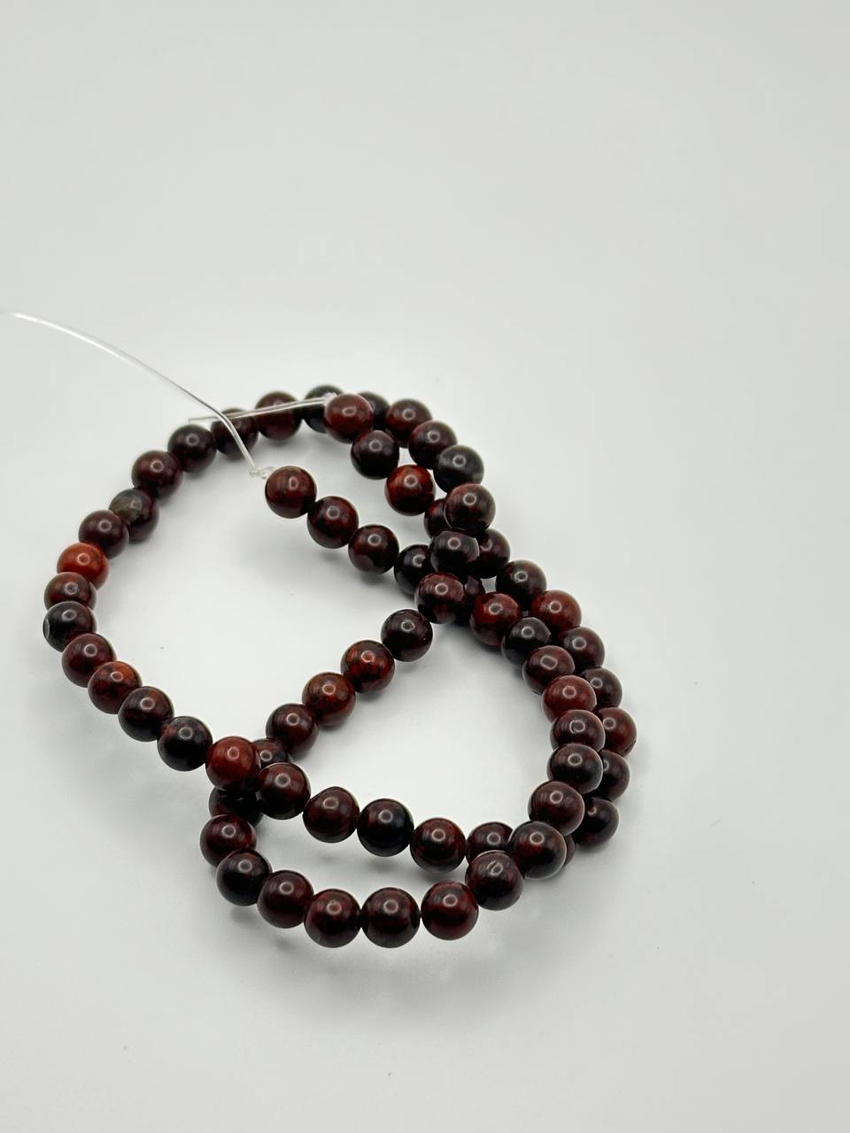 a string of dark red round beads on white surface