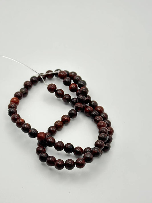 a string of dark red round beads on white surface
