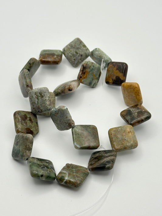 String of green and brown rhyolite beads on a white background