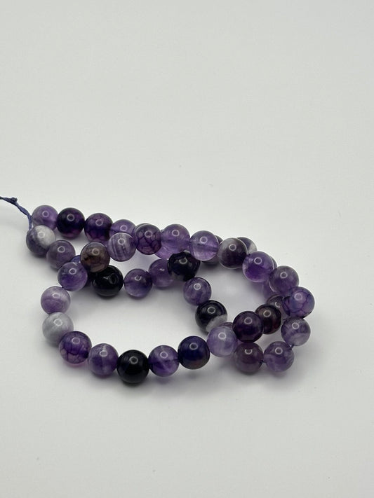 String of purple and black amethyst beads on a white background
