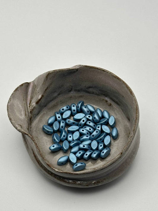 Ceramic bowl with blue irisduo beads on a white background