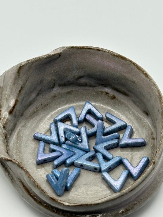 Blue geometric ceramic beads  in a circular arrangement on a gray background