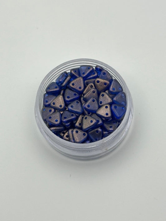 Jar of blue and bronze triangle-shaped beads on a white background