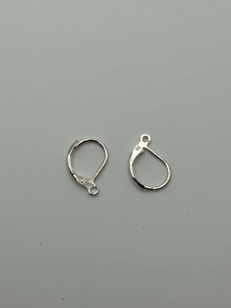 Silver plated leverback earring on grey surface