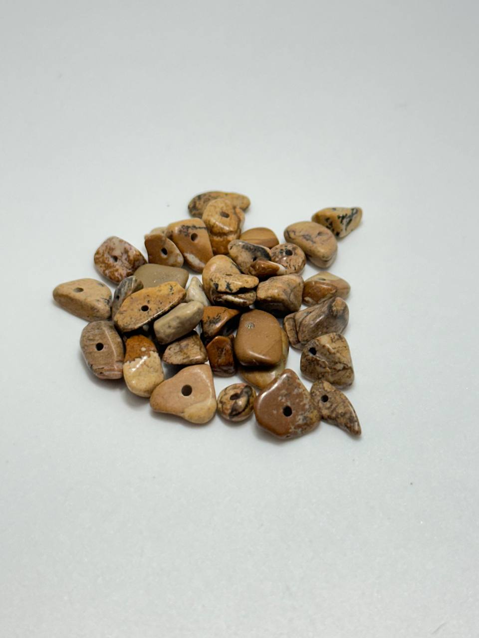 A small pile of picture jasper chip beads on white background