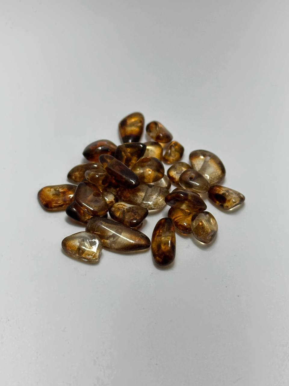 A small pile of amber chip beads on white background