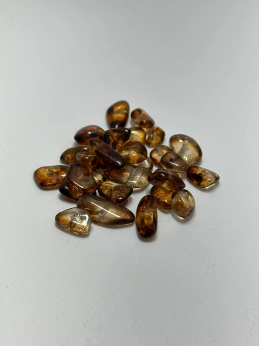 A small pile of amber chip beads on white background