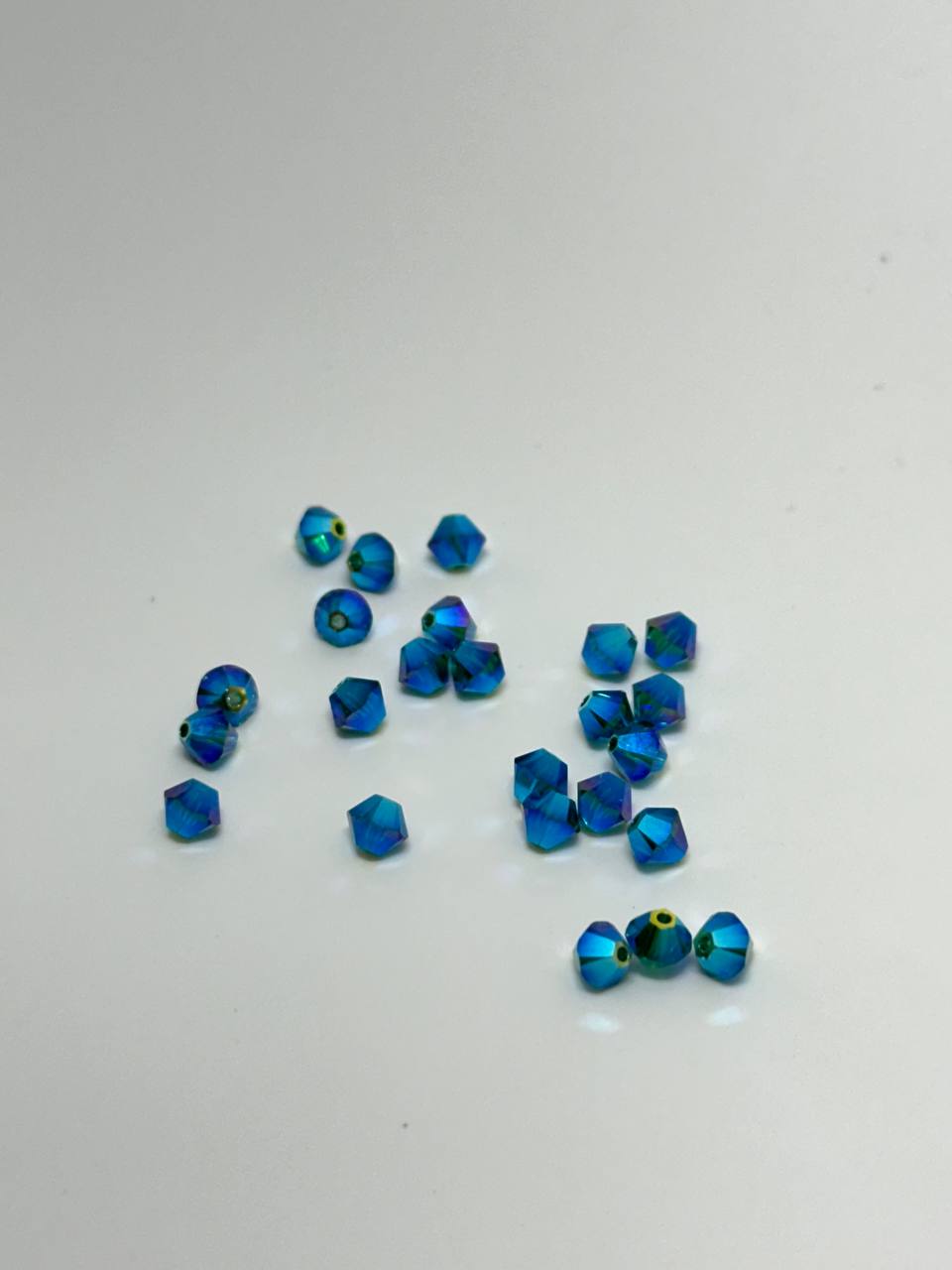 A small pile of 4mm emerald ab x2 bicone beads on white surface
