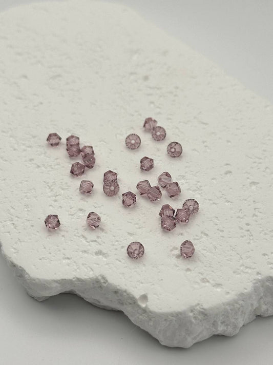 Light amethyst bicone beads on textured surface