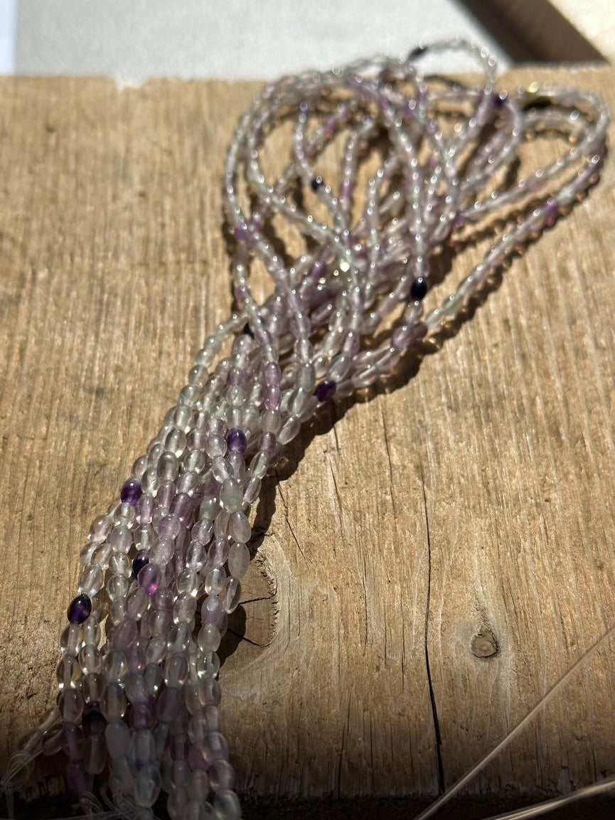 Amethyst tumbled oval beads on wooden surface