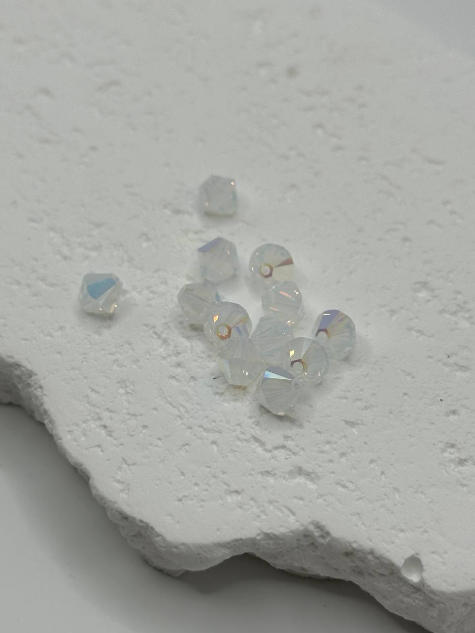 White opal AB crystal bicone beads on white surface