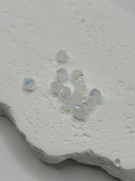 White opal AB crystal bicone beads on white surface