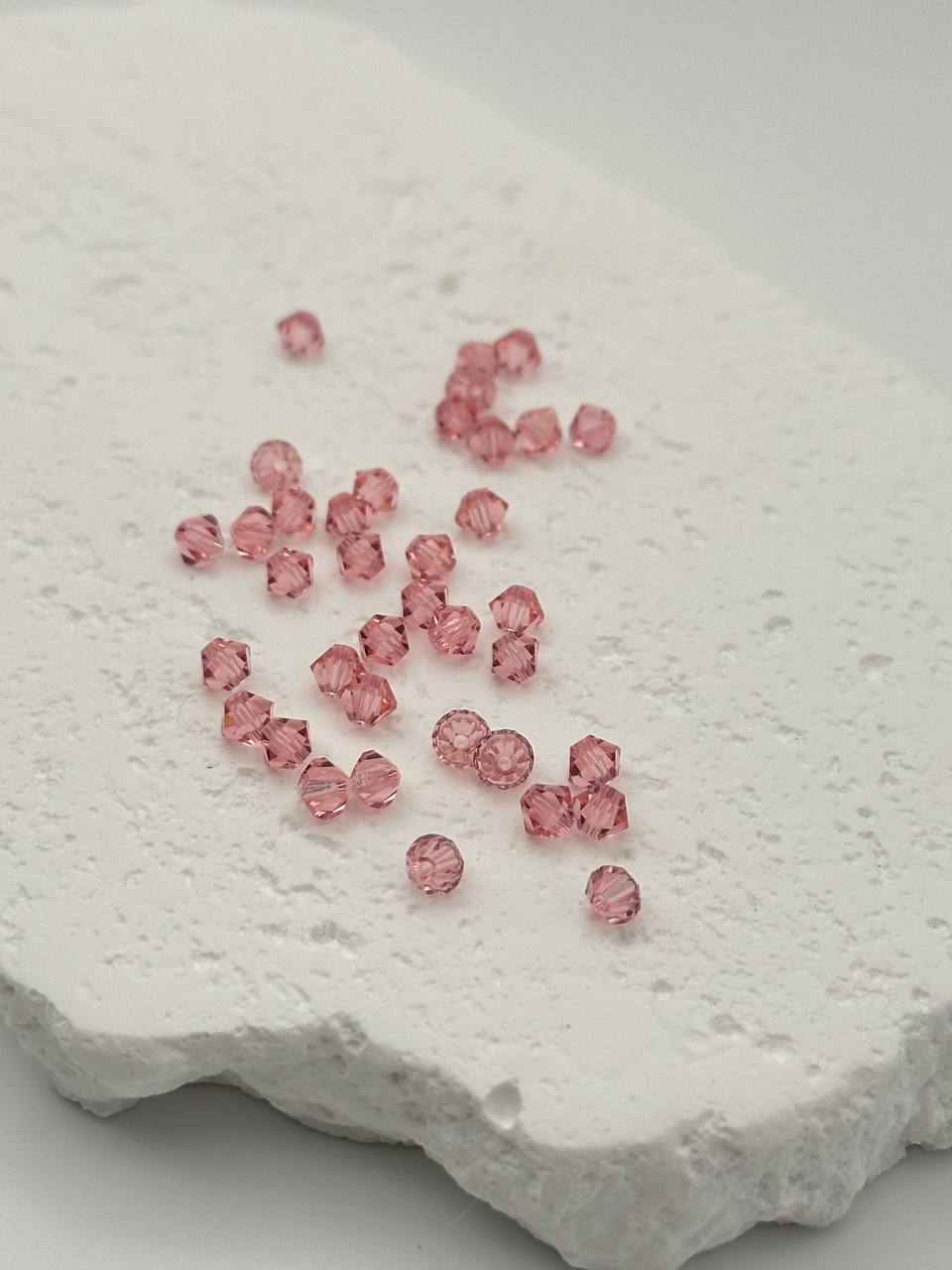 Pink beads scattered on a textured white surface