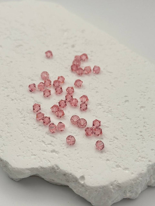 Pink beads scattered on a textured white surface