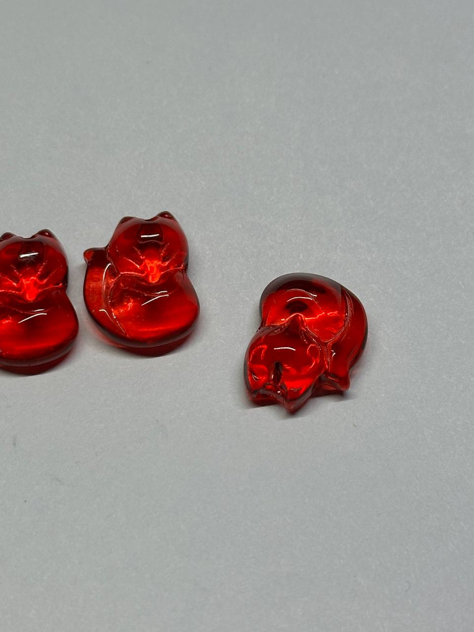 Three red glass figurines of foxes on a gray background