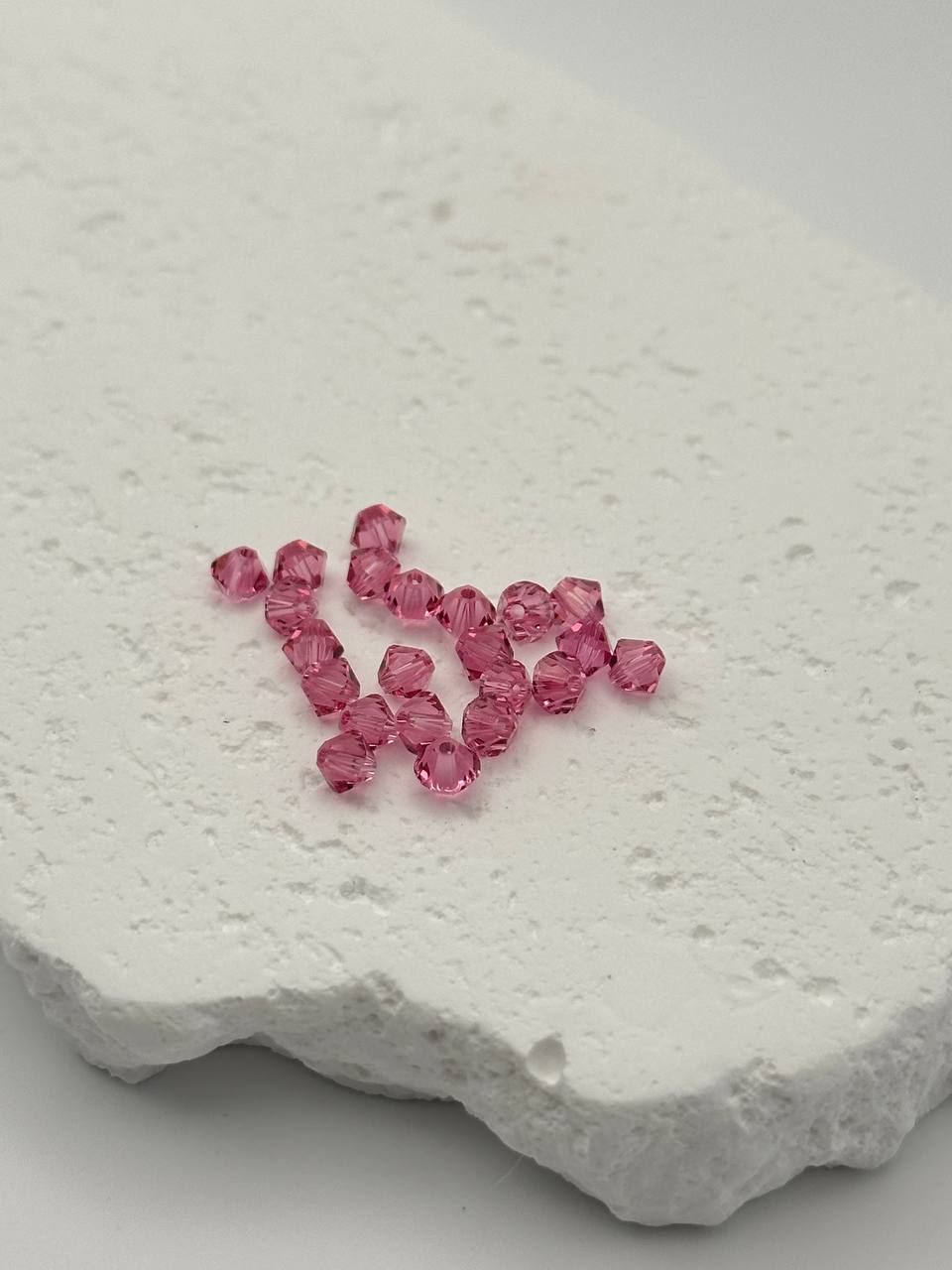 Pink bicone beads on a textured white surface